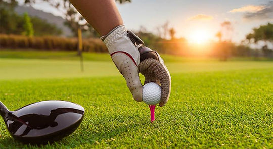 Golfer teeing up a ball at sunset